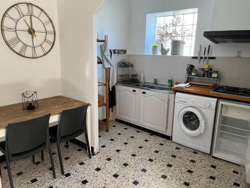 a kitchen with a table and a washing machine at Gîte de la bastide in Monteux