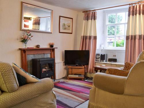 a living room with a fireplace and a television at Beck Cottage in Ambleside
