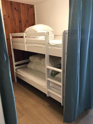 Cette chambre comprend un lit superposé blanc avec des oreillers. dans l'établissement Appartement 4 pers Tour de la Biche skis aux pieds, à Besse-et-Saint-Anastaise