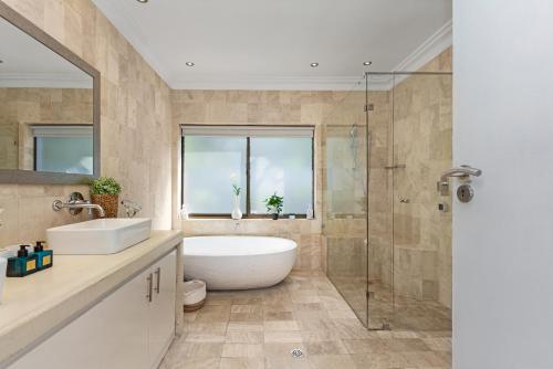 a bathroom with a tub and a sink and a shower at OCEAN BREEZE SUNSET BEACH - Cape Town in Cape Town