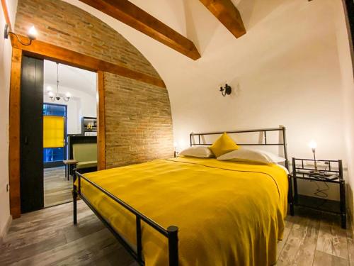 a bedroom with a yellow bed and a brick wall at Apartament 42.2 in Bistriţa