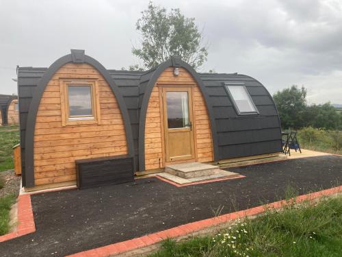 a tiny house with a black roof and a door at Hedgehog Glamping Pod School House Farm in Leighton