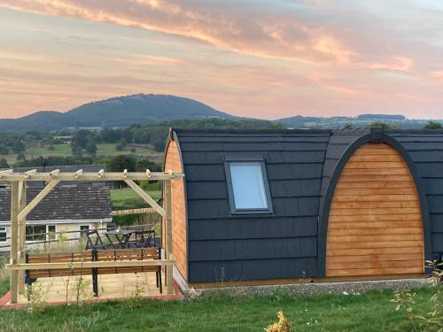 a house with two arched doors and a deck at Hedgehog Glamping Pod School House Farm in Leighton