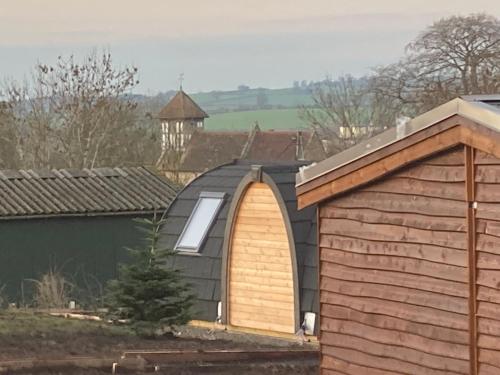 a garage with a wooden door next to a house at Hedgehog Glamping Pod School House Farm in Leighton