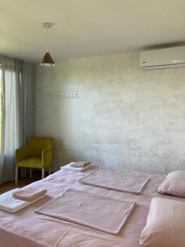 Schlafzimmer mit einem Bett mit rosa Bettwäsche und einem Stuhl in der Unterkunft Kokhta guest house On the mountain in Jvari