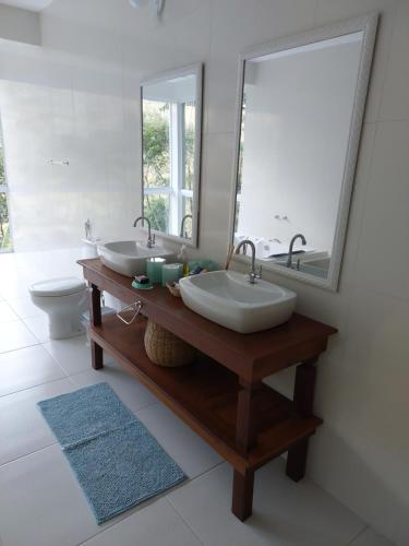 a bathroom with two sinks and a mirror at Lumiar Eco Lodge - Chalé Telhado Verde in Nova Friburgo