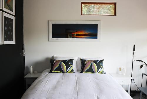 a bedroom with a white bed with a picture on the wall at Nkutu River Lodge in Kloof
