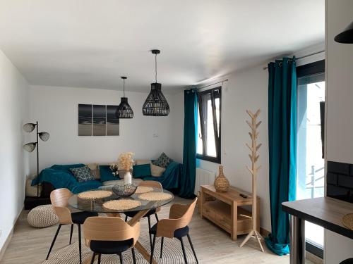 a living room with a blue couch and a table and chairs at La maison de la vallée in Ranville