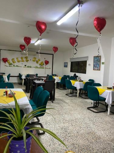 uma sala de jantar com balões de coração vermelho pendurados no tecto em Hotel Villa Ricaurte em Girardot