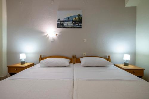 Lucia Hotel Paralia في باراليا كاتيرينّيس: سريرين في غرفة نوم مع مصباحين على الحائط