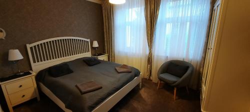 a bedroom with a bed and a chair and a window at Villa Shafaly in Mariánské Lázně