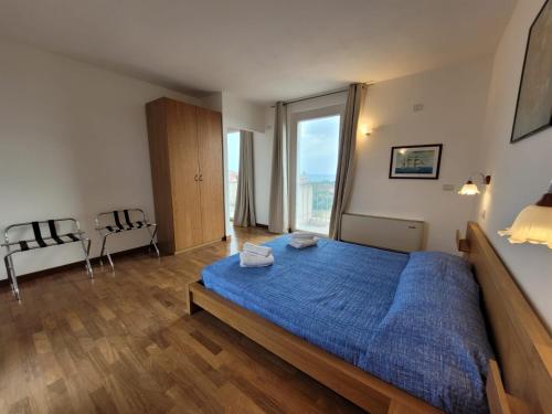 a bedroom with a blue bed and a large window at Villa delle Gazanie -Camera in villa -Vista panoramica sul Golfo in Quartu SantʼElena