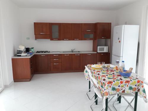 a kitchen with a table and a white refrigerator at Villa delle Gazanie -Camera in villa -Vista panoramica sul Golfo in Quartu SantʼElena