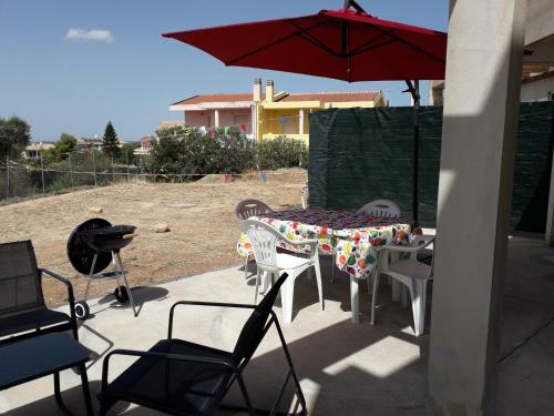 a table and chairs and an umbrella on a patio at Villa delle Gazanie -Camera in villa -Vista panoramica sul Golfo in Quartu SantʼElena