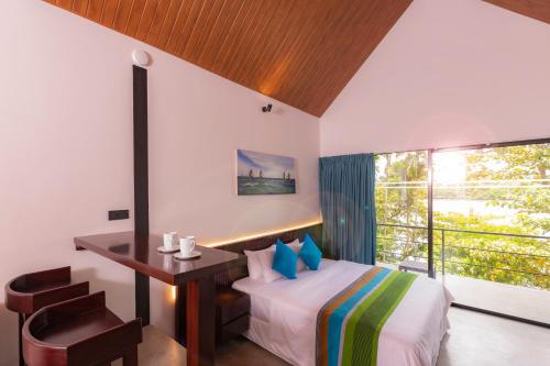 a bedroom with a bed and a desk and a window at Serendipity Lake - Hikkaduwa in Hikkaduwa