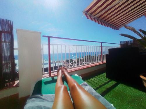 a person laying on a balcony with their feet on a chair at terraza al mar in Pineda de Mar