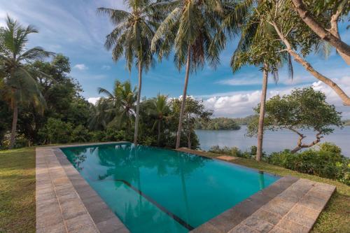 a swimming pool with a view of a river and palm trees at Serendipity Lake - Hikkaduwa in Hikkaduwa