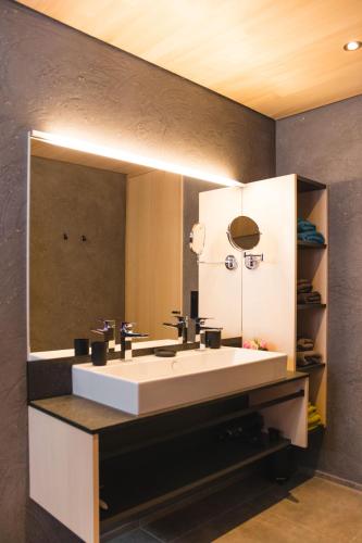a bathroom with a sink and a large mirror at Chalet BergInsel in Balderschwang