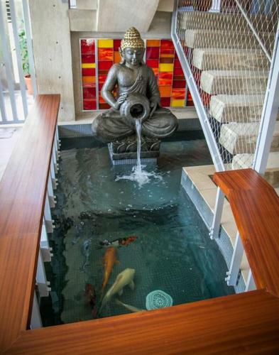 a statue of aitating woman sitting in a koi pond at Dream Inn PR in San Juan