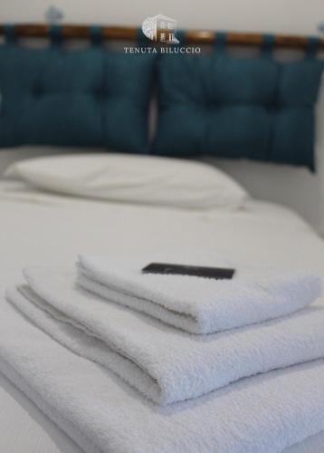 a stack of white towels sitting on top of a bed at TENUTA BILUCCIO B & B in Roccadaspide