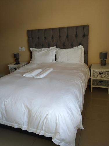 1 cama blanca grande con 2 toallas en On the Wrench, en Ciudad del Cabo
