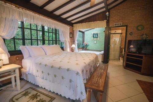 a bedroom with a bed and a television and a tub at Urikana Boutique Hotel in Teresópolis