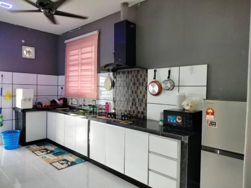 a kitchen with white cabinets and a black counter top at MyHomestay07 in Kangar