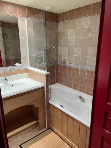 a bathroom with a tub and a sink and a mirror at Les alpages location appartement 108 in Lanslebourg-Mont-Cenis