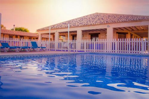 a house with a white fence and a swimming pool at Casas Rurales Alhambra - Lagunas de Ruidera in Alhambra