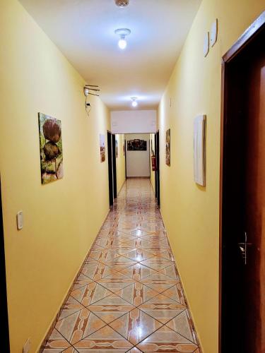a hallway with yellow walls and a tile floor at Hospedaria São Benedito in Guararema