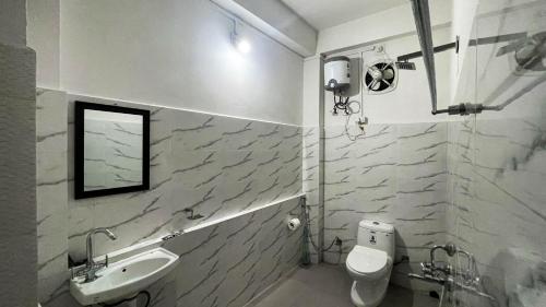 a white bathroom with a sink and a toilet at Abu Homestay in Kohīma