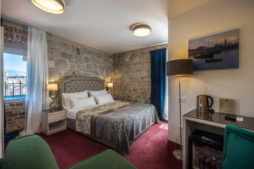 a bedroom with a bed and a stone wall at Hotel Agava Split in Split