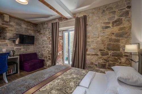 a bedroom with a large bed and a stone wall at Hotel Agava Split in Split