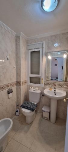 y baño con aseo, lavabo y espejo. en Lovely 2 bed, 2 bath apt with 2 large pools, en Los Alcázares