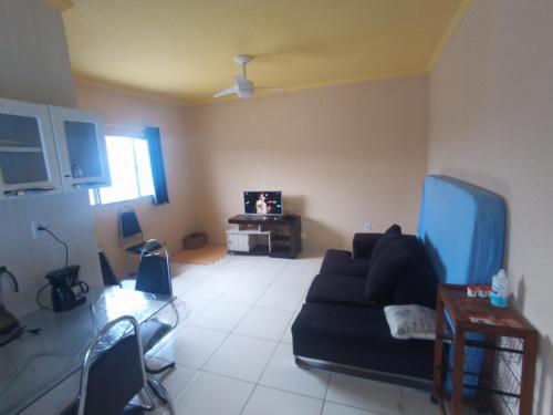 Una sala de estar con un sofá negro y un televisor. en Casa com piscina , churrasqueira, Wi-Fi, em rua de Areia à 1km da praia, bairro sussegado, proíbido uso de som extremamente alto ideal para descansar, en Itanhaém