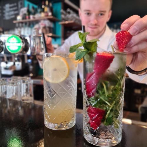 a man is putting a strawberry in two cocktails at Sonnevanck Wijk aan Zee in Wijk aan Zee