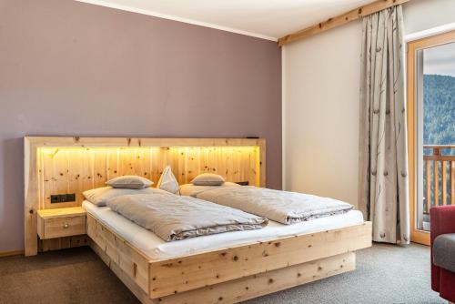 1 dormitorio con cama de madera y ventana grande en Hohenegg Apartment Julian en Sarntal