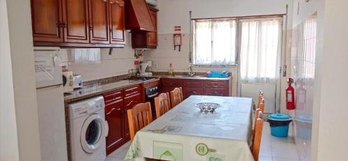 a kitchen with a table and a sink and a washing machine at Baleal Sol Alojamentos in Baleal