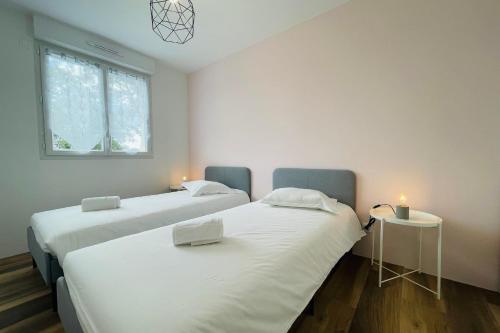 two beds in a room with two candles on them at Spacious modern house near the Golf of Ardrée in Saint-Antoine-du-Rocher