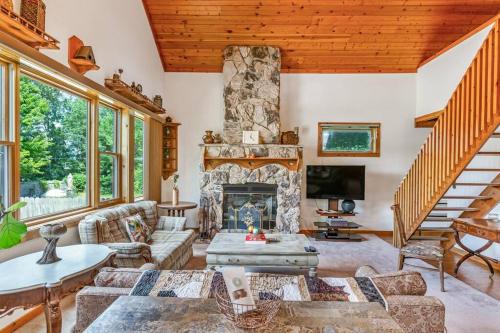 a living room with a stone fireplace and a staircase at Quaint Riverfront Barn in Kankakee