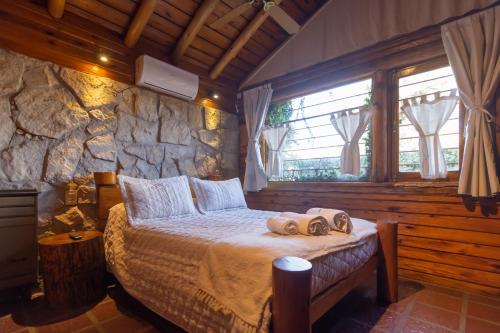 a bedroom with a bed and a stone wall at Cabañas Cumelen in Villa Gesell