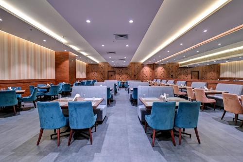 a dining room with tables and blue chairs at Hotel Tip Top International Pune in Pune