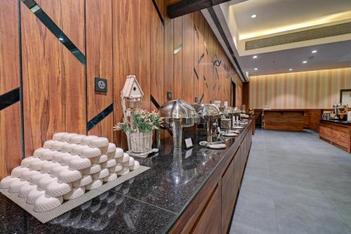 a bar with a row of white plates on a counter at Hotel Tip Top International Pune in Pune