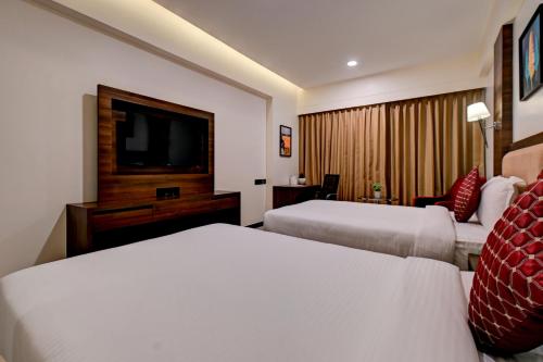 a hotel room with two beds and a flat screen tv at Hotel Tip Top International Pune in Pune
