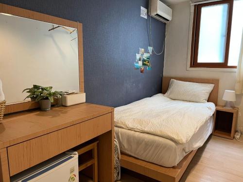 Habitación pequeña con cama y escritorio. en Chris Hostel, en Seúl