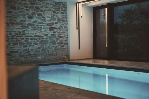 a swimming pool in a room with a stone wall at Domaine Sur Les Sarts in Ohey