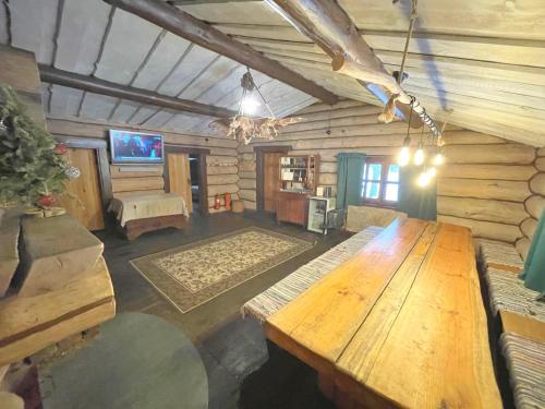 Habitación grande con mesa de madera en una cabaña de madera. en Forest hut Stariy Prud, en Filippovichi