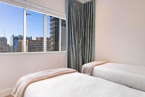 1 dormitorio con 2 camas y ventana con vistas a la ciudad en Stay In Luxury at Stonehill Place, en Ciudad del Cabo