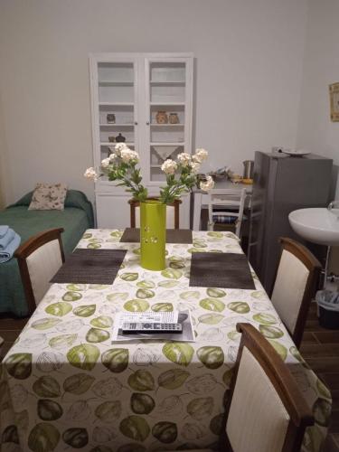 a dining room table with a green vase with flowers on it at Bouganville in Viverone