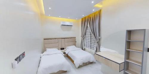 1 dormitorio con 2 camas y ventana en شاليه بلاك وايت, en Al Harazat